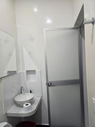 a white bathroom with a sink and a shower at La casa de Delia armero guayabal in Guayabal