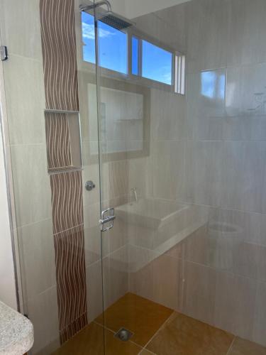 a bathroom with a glass shower with a sink at La casa de Delia armero guayabal in Guayabal