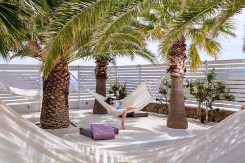 a woman sitting in a hammock between two palm trees at Pietra e Mare - Mykonos Moments in Kalo Livadi