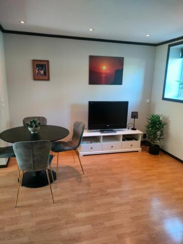 Una sala de estar con televisión, mesa y sillas. en Romslig leilighet på Træleborg i Tønsberg, en Tønsberg