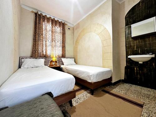 a bedroom with two beds and a sink in it at Hotel Paris in Sousse