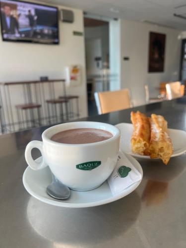 a cup of coffee on a plate with a pastry at Espacio San Juan de la Cruz in Fontiveros
