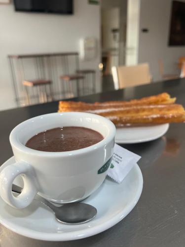 a cup of hot chocolate and a plate of bread at Espacio San Juan de la Cruz in Fontiveros
