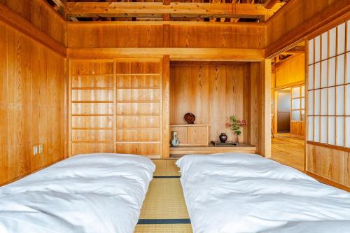 two beds in a room with wooden walls at わらほんど in Naha