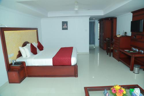 a bedroom with a bed and a desk and a television at hotel savera park in Trichūr