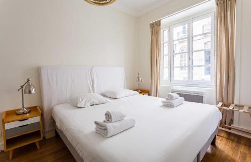 une chambre blanche avec deux lits avec des serviettes dessus dans l'établissement Le Chapitre - Appartement cosy, centre historique, à Rennes