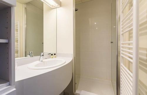une salle de bain blanche avec un lavabo et une douche dans l'établissement Le Chapitre - Appartement cosy, centre historique, à Rennes