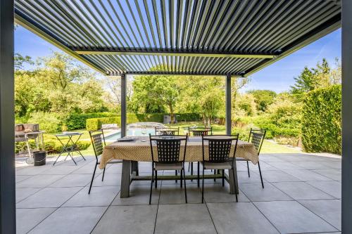 a patio with a table and chairs under a pergola at Kerwall - Maison d'hôtes in Malville