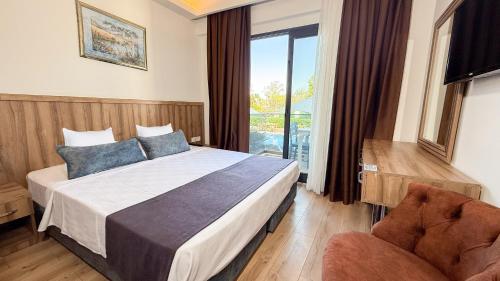 a bedroom with a bed and a chair and a window at Çınar Butik Hotel Bodrum in Bodrum City