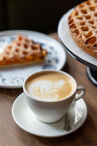 a cup of coffee on a table with waffles at Townhouse Den Haag in The Hague