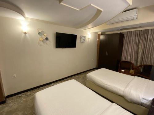 a hotel room with two beds and a flat screen tv at Al-Sadier Place Hotel & Restaurant in Baghdad