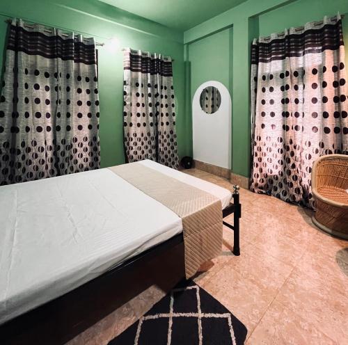 a bedroom with a bed with green walls and curtains at Townsville in Jorhāt