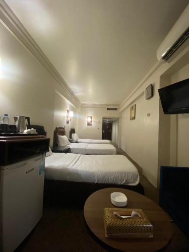 a hotel room with two beds and a table at Al-Sadier Place Hotel & Restaurant in Baghdad