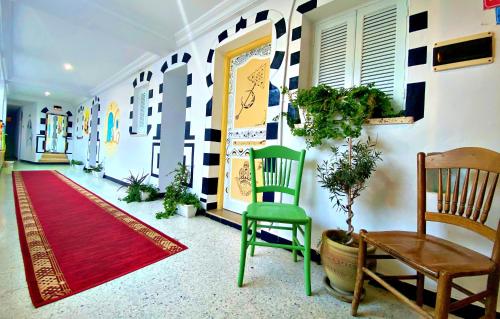 a hallway with a green chair and a red rug at Hotel Paris in Sousse