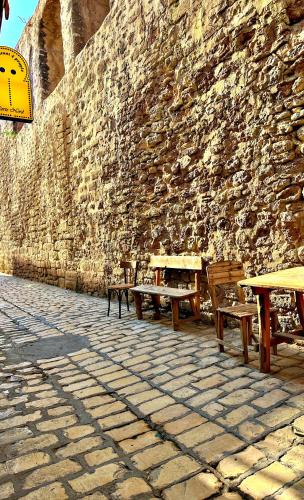 a stone wall with wooden tables and benches next to a wall at Hotel Paris in Sousse