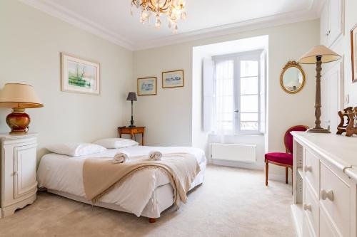 - une chambre blanche avec un lit et un lustre dans l'établissement Duchesse - Intramuros - Ascenseur - Coquet - Wifi, à Vannes