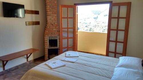 a bedroom with a bed with a fireplace and a window at Pousada Caminho de Minas in Bocaina de Minas