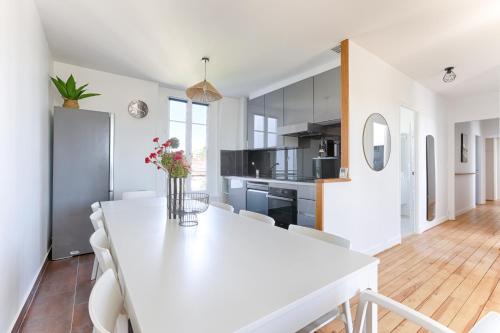 a kitchen and dining room with a white table and chairs at Appartements à Champigny-Sur-Marne - 30 minutes de Disneyland in Champigny-sur-Marne