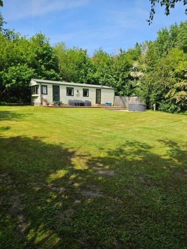 a house in the middle of a grassy yard at Silver Birch Nabb Lane Hot tub near Alton Towers in Combridge