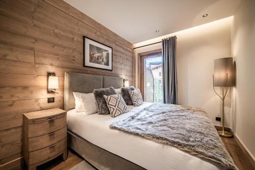 une chambre avec un lit et un mur en bois dans l'établissement Apartment Osprey Les Gets - by EMERALD STAY, aux Gets