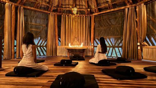 エル・ザイノにあるSenda Loto Retreat Meditation Yogaの二人の女性がヨガをしている部屋に座っている