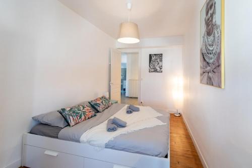 une chambre avec un lit dans une pièce blanche dans l'établissement KASA ZAMBEZE - Spacious - Equipped - Wi-Fi, à Saint-Étienne