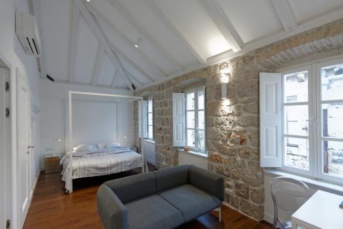 a bedroom with a bed and a chair and windows at Apartments Eleganca in Dubrovnik