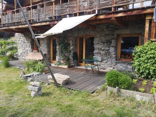 une terrasse en bois devant une maison en pierre dans l'établissement Appartement de plain pied dans chalet, à Saint-Sorlin-dʼArves