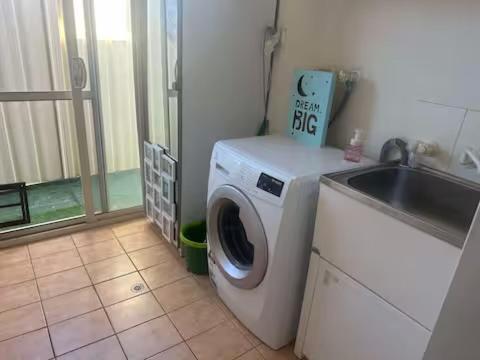 a washing machine in a kitchen next to a sink at Master room with private bathroom in Perth