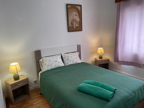 a bedroom with a green bed with two lamps at Tiny apartment near the airport in Ponta Delgada