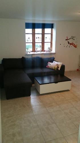 a living room with a black couch and a coffee table at Rundvejen Guest House in Aalborg