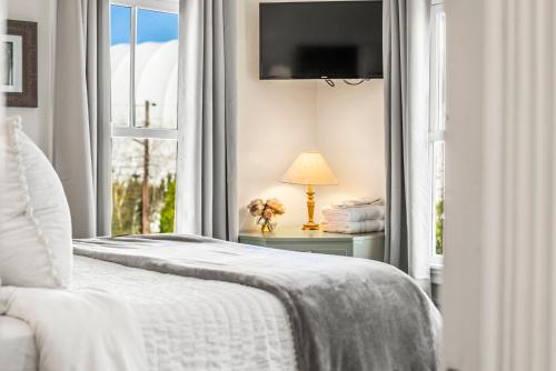 a white bedroom with a bed and a window at Historic Seaside Downtown Mystic Home Walk to Seaport in Stonington