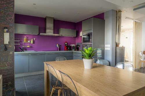 une cuisine avec des murs violets et une table en bois dans l'établissement Le Sans Soucis, à Colmar
