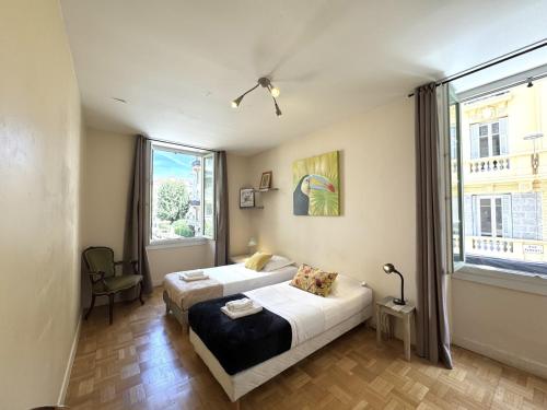 une chambre avec deux lits et une grande fenêtre dans l'établissement ApartHotel Riviera - Hotel des Postes 2 - City center Massena, à Nice