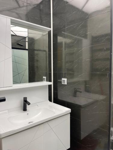 a white bathroom with a sink and a mirror at Avant Daireleri in Baku