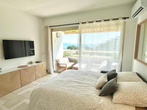 une chambre avec un grand lit et une grande fenêtre dans l'établissement Marina Baie studio vue mer et jardin avec clim, à Villeneuve-Loubet