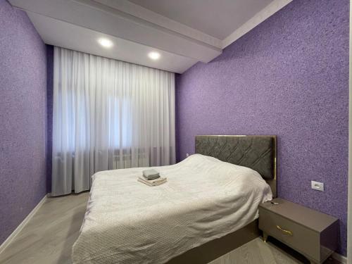 a bedroom with a bed with a purple wall at Avant Daireleri in Baku