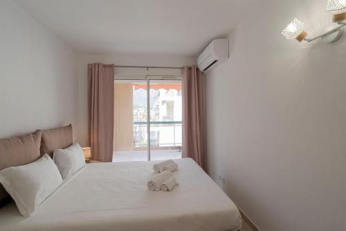 un ours en peluche assis sur un lit avec une fenêtre dans l'établissement Stylish Apartment S8329, à Roquebrune-Cap-Martin