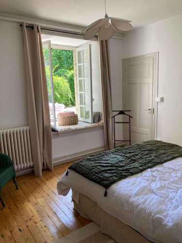a bedroom with a bed and a large window at Conciergerie du château in Gevingey
