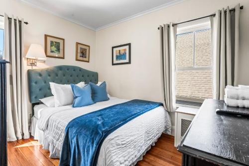 a bedroom with a bed with a blue headboard and a window at Historic Seaside Downtown Mystic Home Walk to Seaport in Stonington