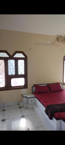 a bedroom with a red bed and two windows at Nakwa's mansion in Malpe
