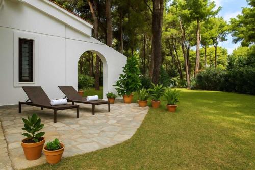 eine Terrasse mit Stühlen und Topfpflanzen im Hof in der Unterkunft Paradise Found at Thalia's Poolside Villa in Sani Beach