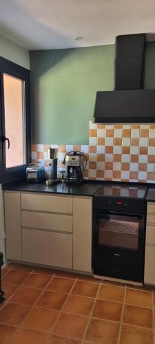- une cuisine équipée d'un four avec plaques de cuisson noires à côté d'une fenêtre dans l'établissement La BERGERIE, à Pélissanne