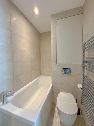 a white bathroom with a tub and a toilet at Whitfield Street Apartments in London