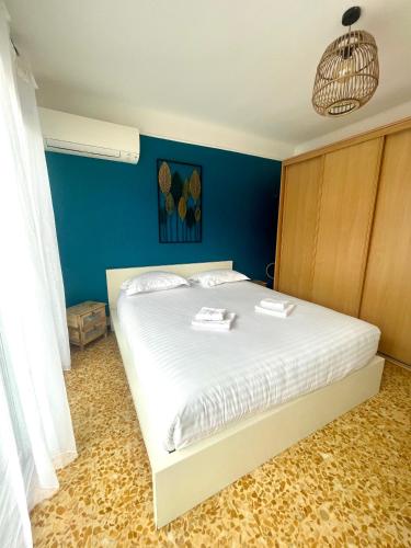 une chambre avec un lit blanc avec un mur bleu dans l'établissement La mer, accès direct et calme, terrasse, à Roquebrune-Cap-Martin