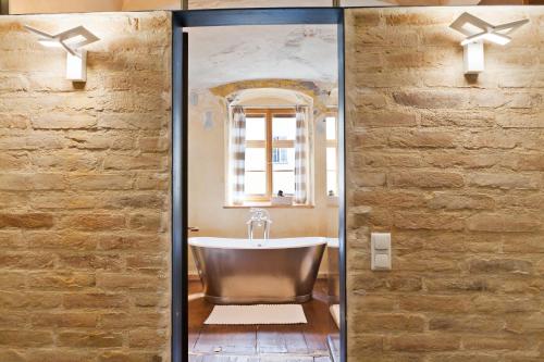 a bath tub in a bathroom with a stone wall at Hotel David an der Donau in Regensburg