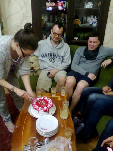 a group of people sitting around a table cutting a cake at Giorgi's Homestay in Kutaisi