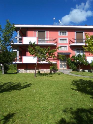 a red building with a grass yard in front of it at Casa Rosciano in Rosciano