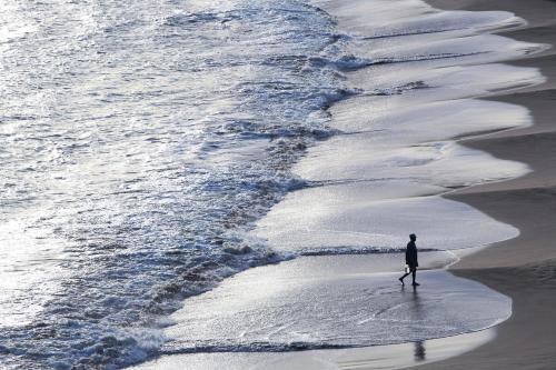 a man walking on the beach near the water at The Ocean House Antigua in Cedar Grove