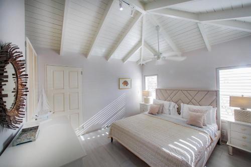 a white bedroom with a bed and a window at The Ocean House Antigua in Cedar Grove